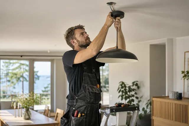 Technician installing a ceiling light fixture